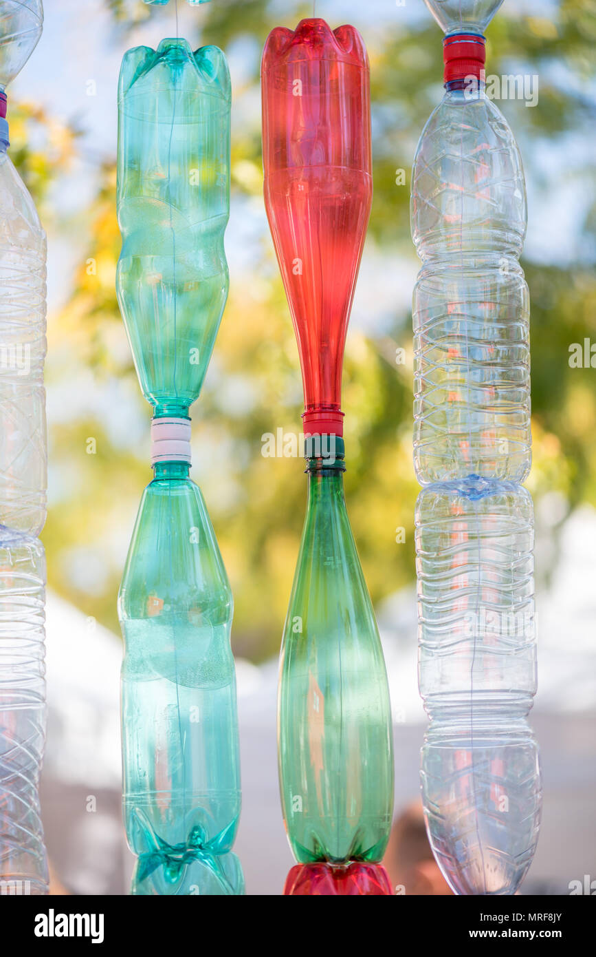 Wand von bunten leere Plastikflaschen an einem sonnigen Tag mit grünen Bäumen Hintergrund Stockfoto