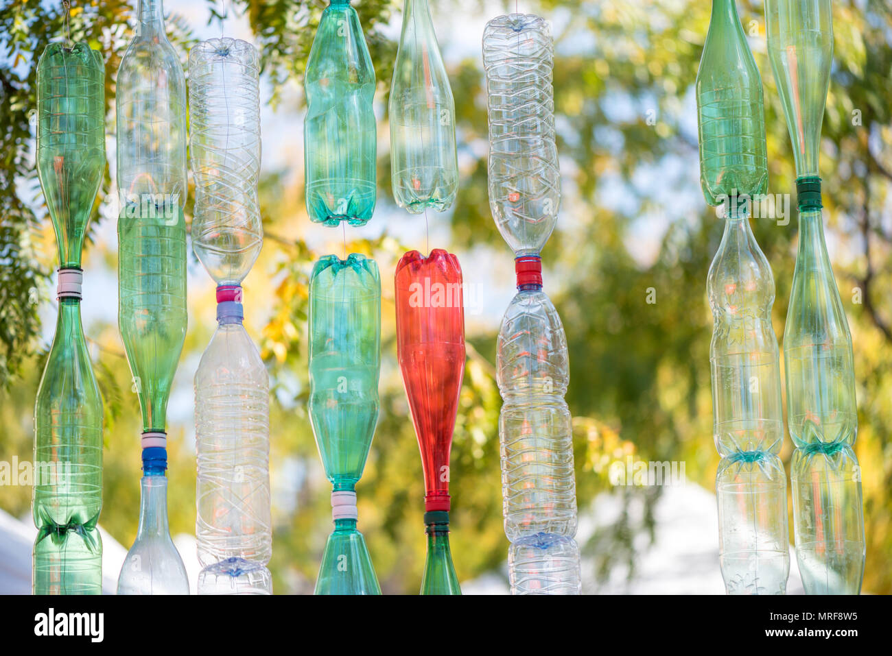 Wand von bunten leere Plastikflaschen an einem sonnigen Tag mit grünen Bäumen Hintergrund Stockfoto