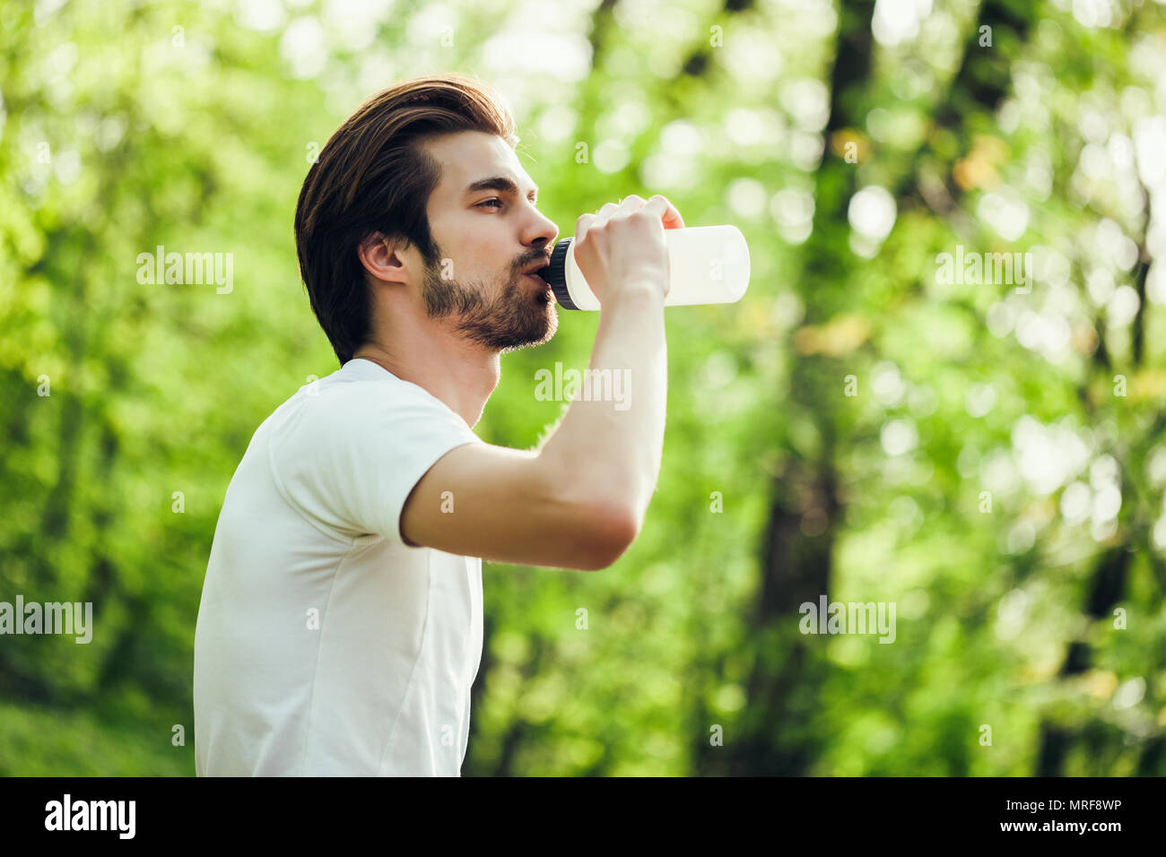 Junge Mann ist das Trainieren im Park. Er ist Trinkwasser. Stockfoto