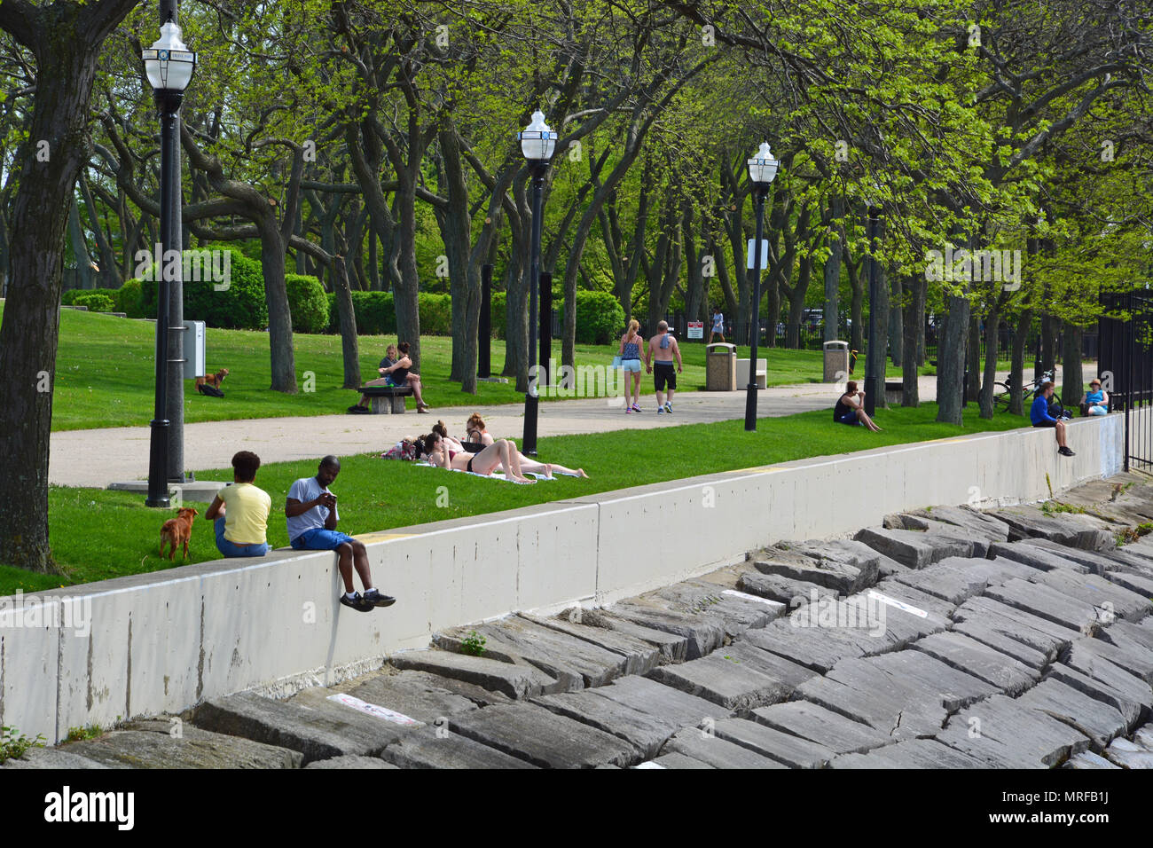 Besucher sitzen auf der Mauer bei Milton Lee Olive Park in Chicago's Streeterville Nachbarschaft, einer Halbinsel Land nördlich von Navy Pier. Stockfoto