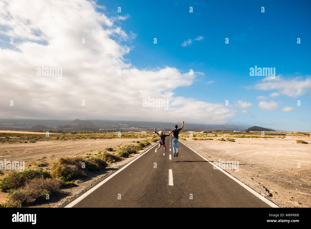 Nettes Paar zu Fuß und mit Zufriedenheit und Freude auf eine lange infinte Straße Sprung für gemeinsames Leben Konzept. schönen Himmel und Wüste um Mann und Frau pe Stockfoto