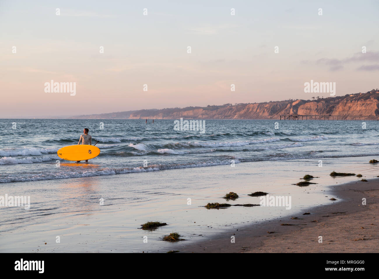 Ein Stand up paddleboarder (SUP) blickt zurück in Richtung der untergehenden Sonne nach einem Abend Paddeln im La Jolla Shores in San Diego. Stockfoto