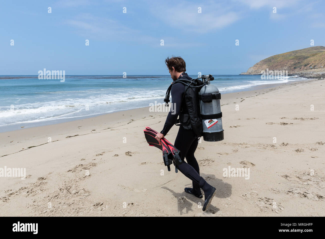 Ein Scuba diver Spaziergänge in Richtung Ozean und für einen Strand Tauchen (shore Dive) an einem sonnigen Tag in Malibu, Kalifornien. Stockfoto