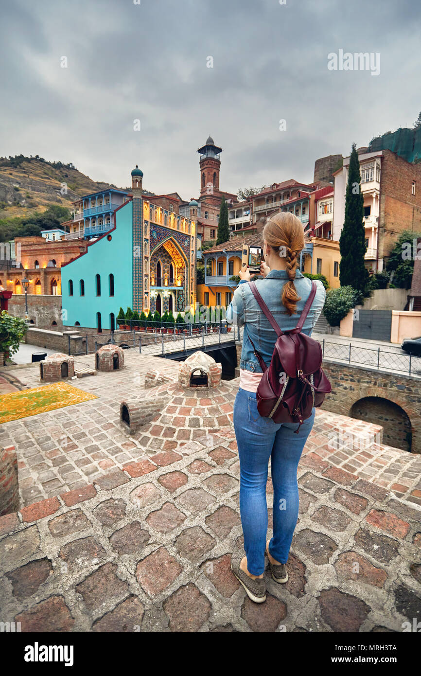 Touristische Frau in braunen Sakko unter Bild der öffentlichen Schwefelsäure Badewanne von Ihrem Smartphone in Tiflis, Georgien Stockfoto