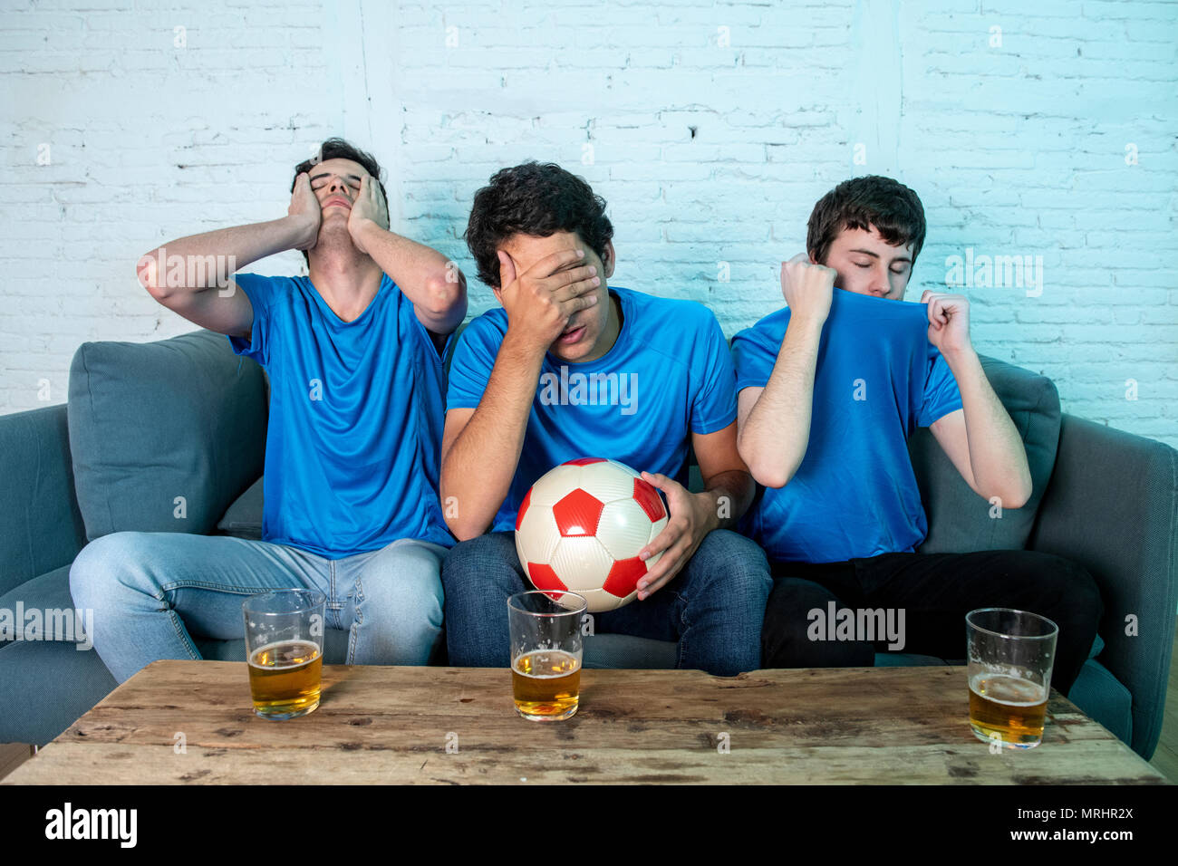 Junge Gruppe der kaukasischen Fußballfans enttäuscht gerade ein Fußballspiel auf der Couch. Stockfoto