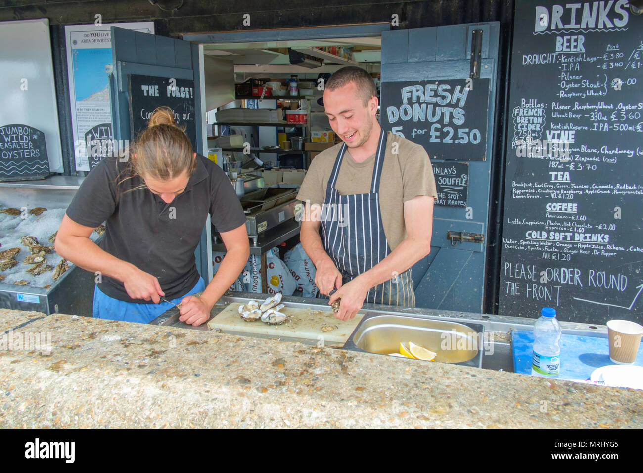 Zwei Männer Vorbereitung Austern in einem Shop auf Whitstable Strandpromenade in Whitstable, Kent, England, UK. Stockfoto