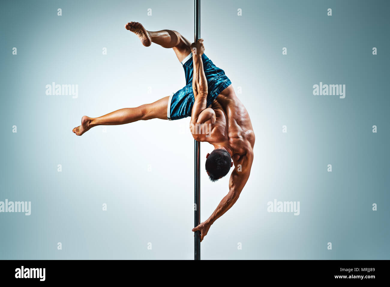 Junge starke Mann Pole Dancing auf blauem und weißem Hintergrund Stockfoto