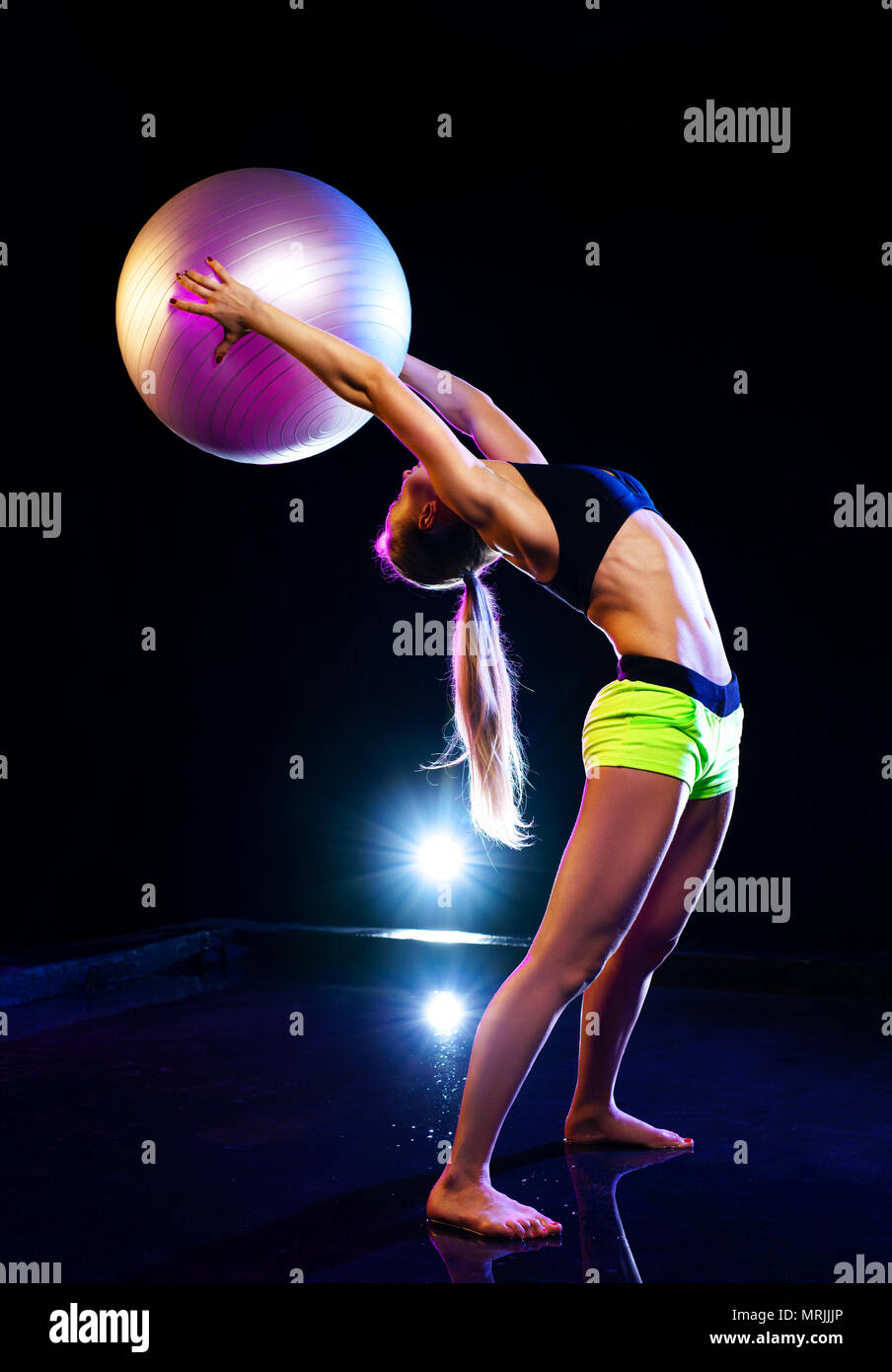 Junge sport Frau Training mit Fitness Ball im schwarzen Studio Innenraum Stockfoto