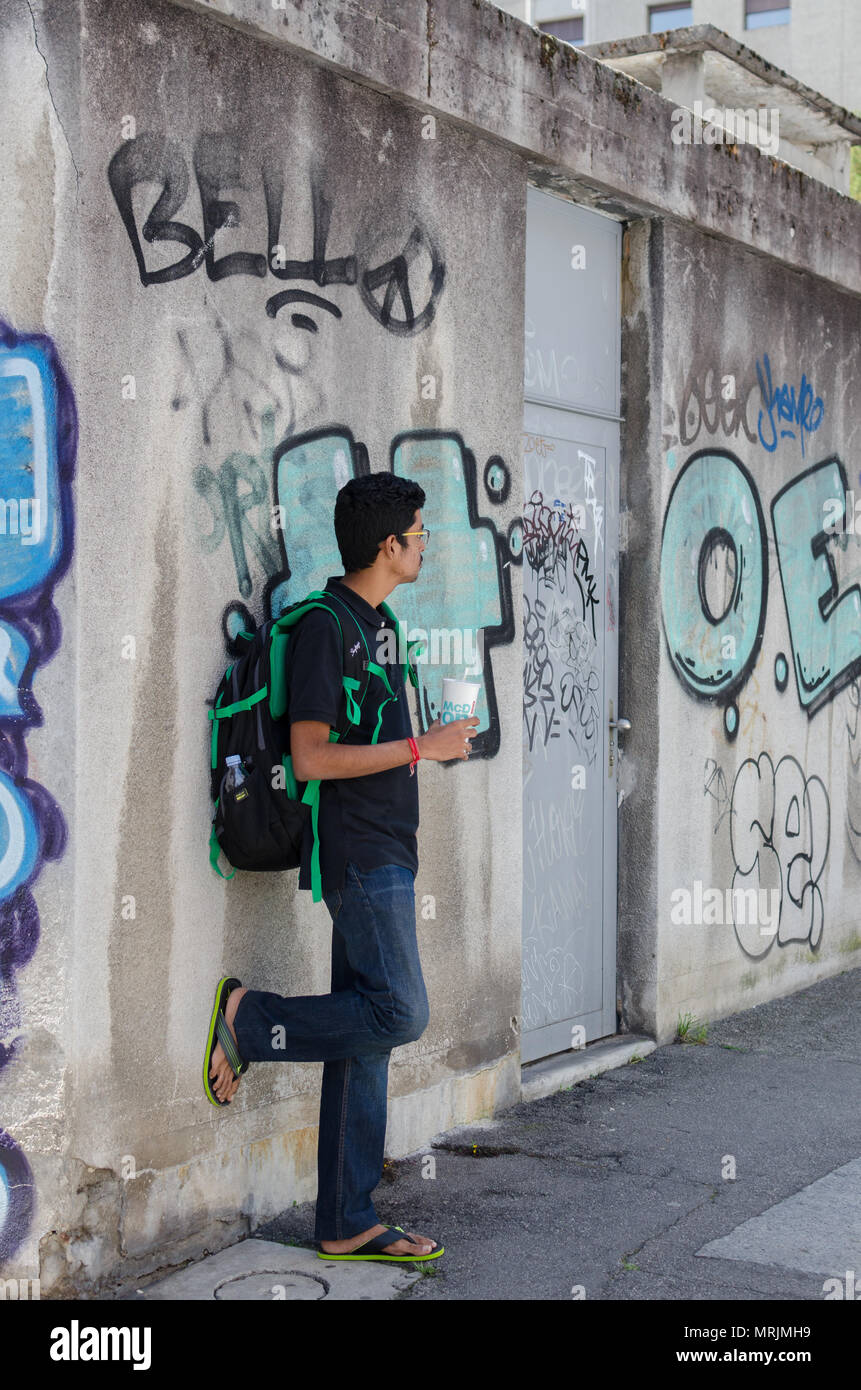In voller Länge Porträt der jungen Erwachsenen indischer Junge gegen Graffiti, Wand mit Rucksack posiert, weg von der Kamera. Stockfoto