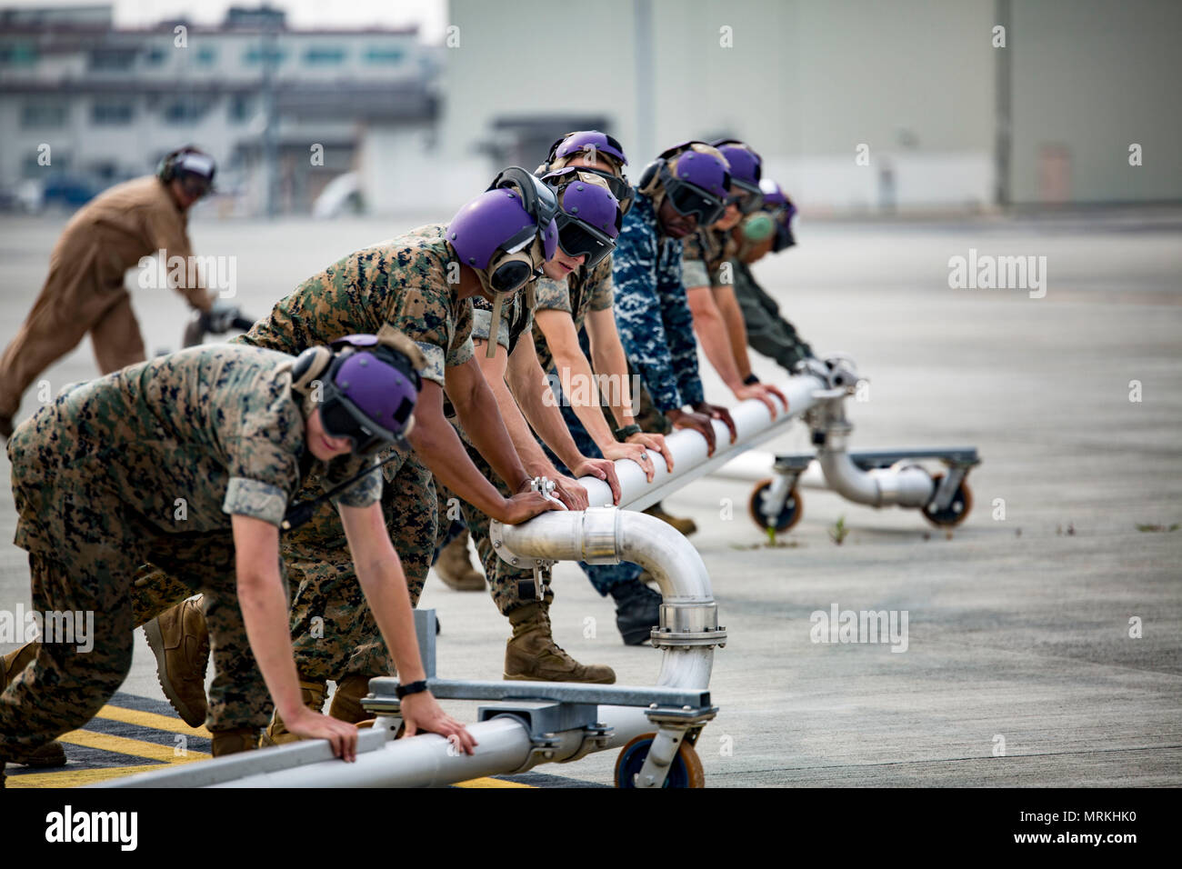 Us-Marines, die US-amerikanischen Matrosen und Master arbeit Unternehmer mit Sitz und Hauptverwaltung Squadron (H&HS) Kraftstoffe Division bereiten eine Kraftstoffleitung während eines Proof of Concept für heiße Betanken des Marine Corps Air Station Iwakuni, Japan, 20. Juni 2017 zu drücken. Der Proof of Concept für geprüfte Sicherheit und sorgte dafür, dass alle Geräte ordnungsgemäß funktioniert. Ausstehende Genehmigung aus der Air Station kommandierenden Offizier und der Defense Logistics Agency, wieder heißen tanken Gruben können Flugzeuge zu schnell ohne Herunterfahren ihre Motoren, Tanken, erhöht die Betriebsbereitschaft. (U.S. Marine Corps Foto b Stockfoto