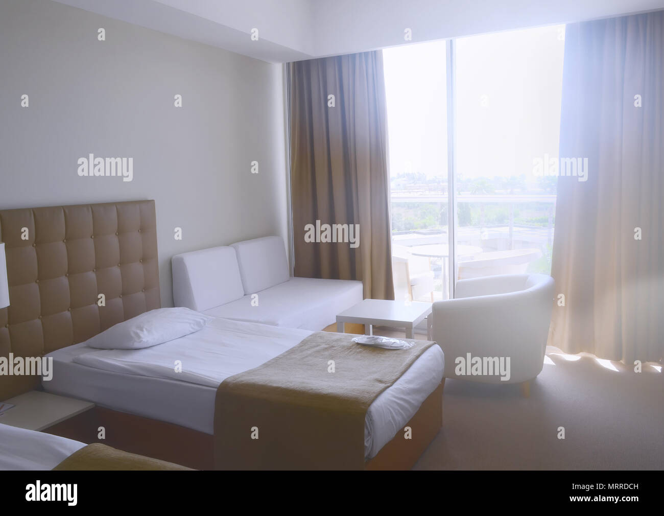 Sonnige Zimmer im Hotel in hellen Farben und mit zwei Einzelbetten, Sofa und Sessel Stockfoto