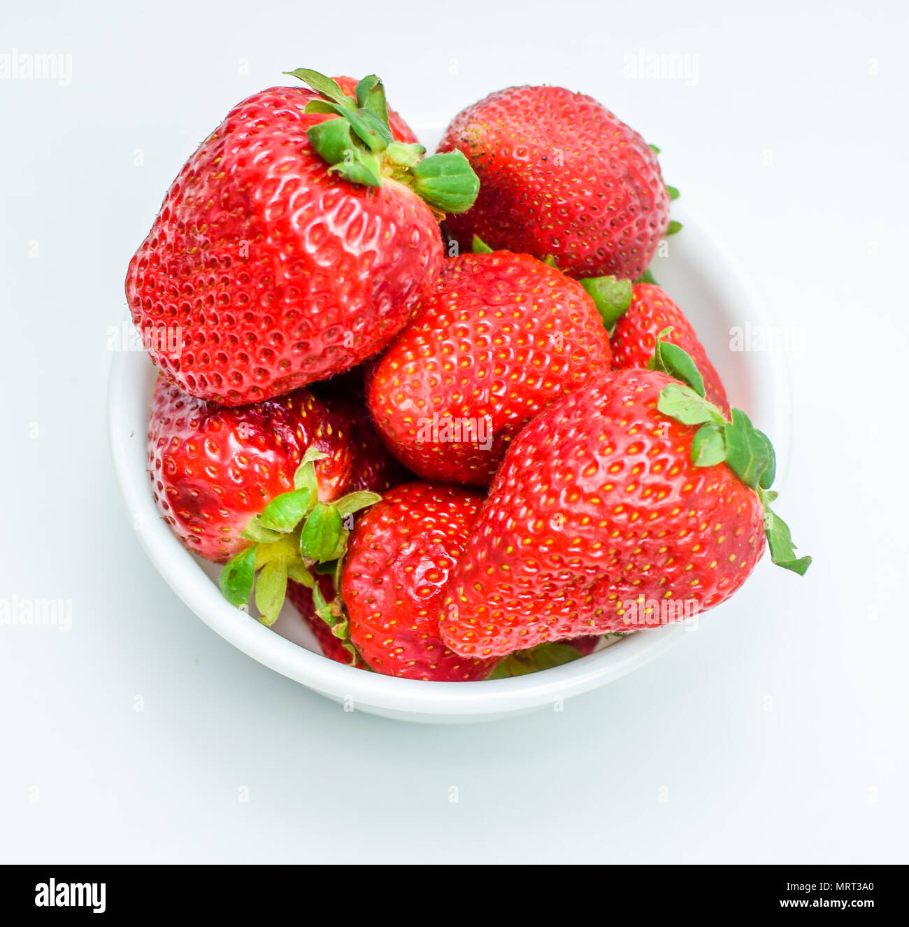 Frische reife Erdbeeren mit Blättern in einer Schüssel auf weißem Hintergrund Stockfoto