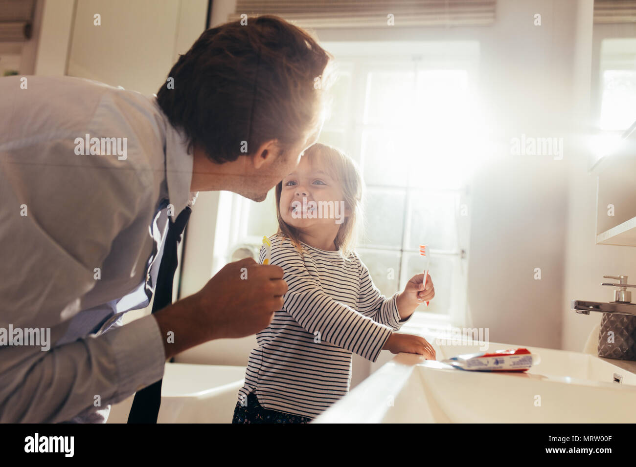 Vater und Tochter Zähneputzen im Bad stehen und einander an. Mann seine Tochter, wie die Zähne zu putzen. Stockfoto