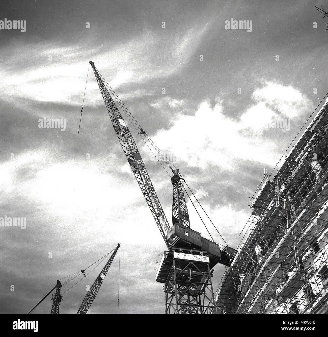 1960, historische, Blick vom Boden bis zu einem McAlpine Kran hoch in den Himmel schauen. In dieser Ära, London erleben Sie einen Bauboom als post-ww2 Bombe Websites und beschädigte Gebäude wurde in riesige Beton Turm und Bürogebäude umgebaut. Die McAlpine Bauunternehmen - Sir Robert McAlpine - war immer vorhanden und renommierten Namen im Bau mit Wembley Stadion und dem Dorchester Hotel zwischen den Kriegen. Stockfoto