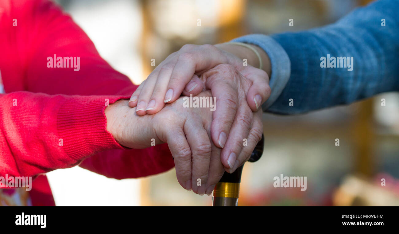 Mädchen legt ihre Hand auf die Hand der eine alte Frau mit Stock Stockfoto