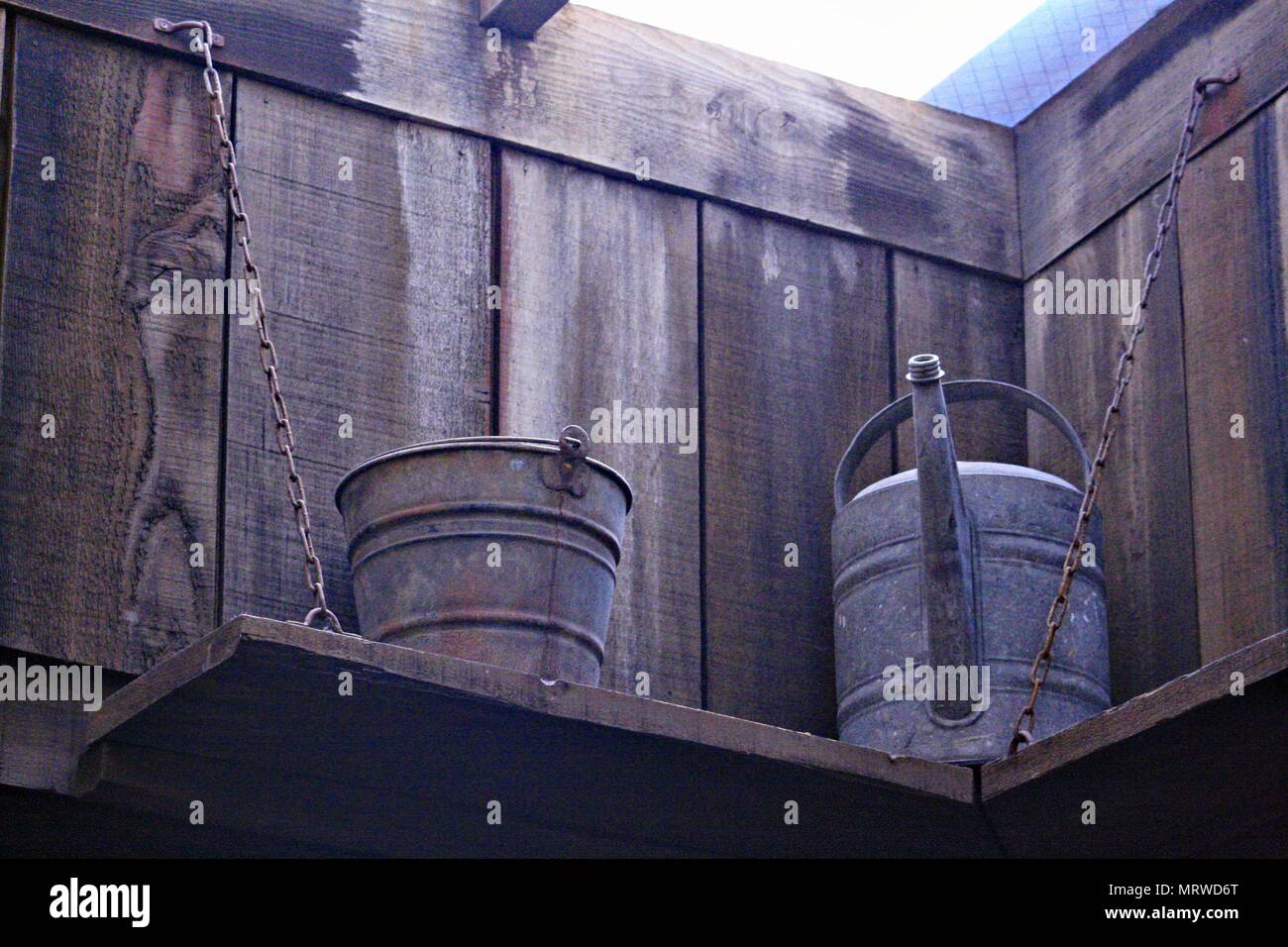 Ein antikes Zinn Eimer und Gießkanne angekettet an einem Regal zu bewahren Stockfoto