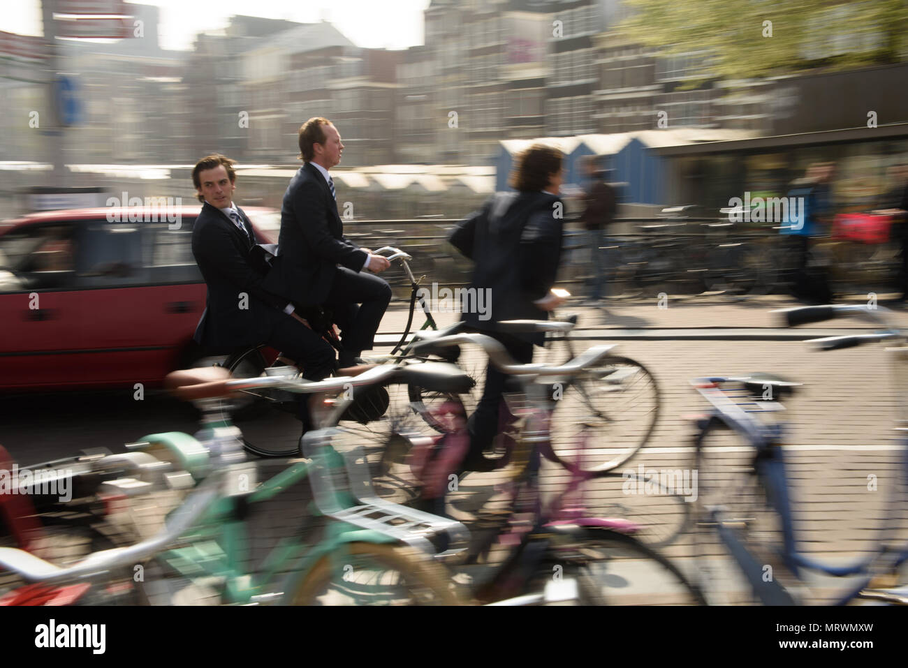 Amsterdam, Netherlands-April 24, 2015: Zwei Männer mit dem Fahrrad zur Arbeit in der belebten, belebte Straßen von Amsterdam, Niederlande. Stockfoto