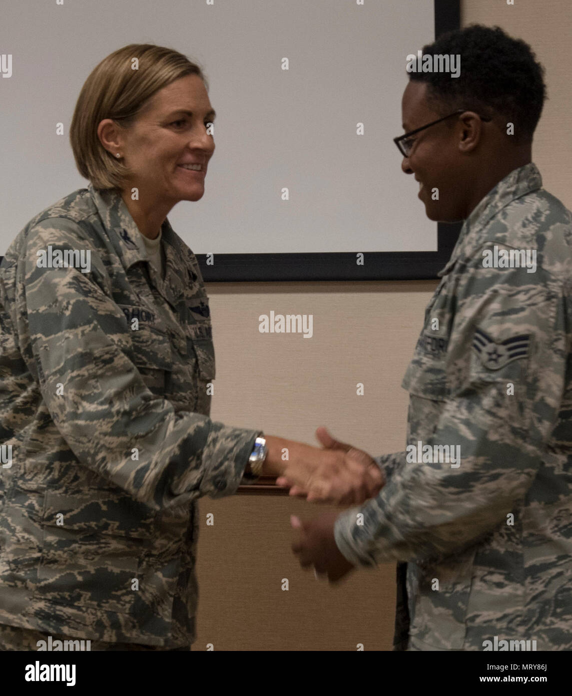 Us Air Force Colonel Jennifer Kurz, Links, Hände Älterer Flieger Janiqua Robinson, Rechts, ihre erste Medaille als Kommandeur der 23d Flügel, 12 Juli, 2017 bei Moody Air Force Base, Ga. Robinson ist ein begabter Fotojournalist für die 23 d-Wing Public Affairs Office, dem 1. Platz in Air Combat Command Media Contest und Platz 2 in der Abteilung für Verteidigung Ebene gewonnen hat. (U.S. Air Force Foto von 1 Lt Kaitlin Toner) Stockfoto