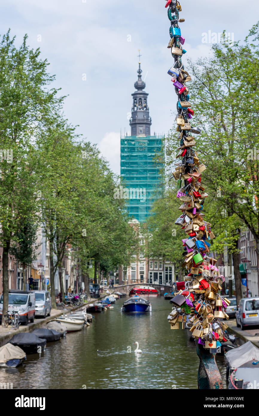 Kette der Vorhängeschlösser zum Gedenken an Liebe, mit Canal im Hintergrund und Turm im Gerüst und grüne Netz umwickelt. Stockfoto