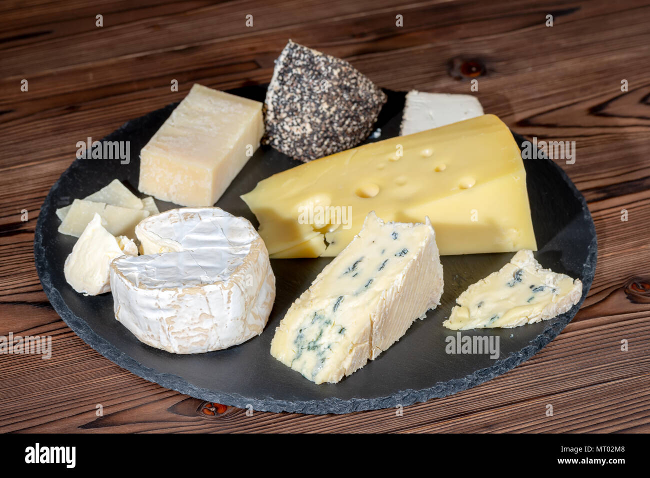 Teile verschiedener Arten von frischen Käse auf schwarzem Schiefer Textur über Holz- Tabelle, in der Nähe Stockfoto
