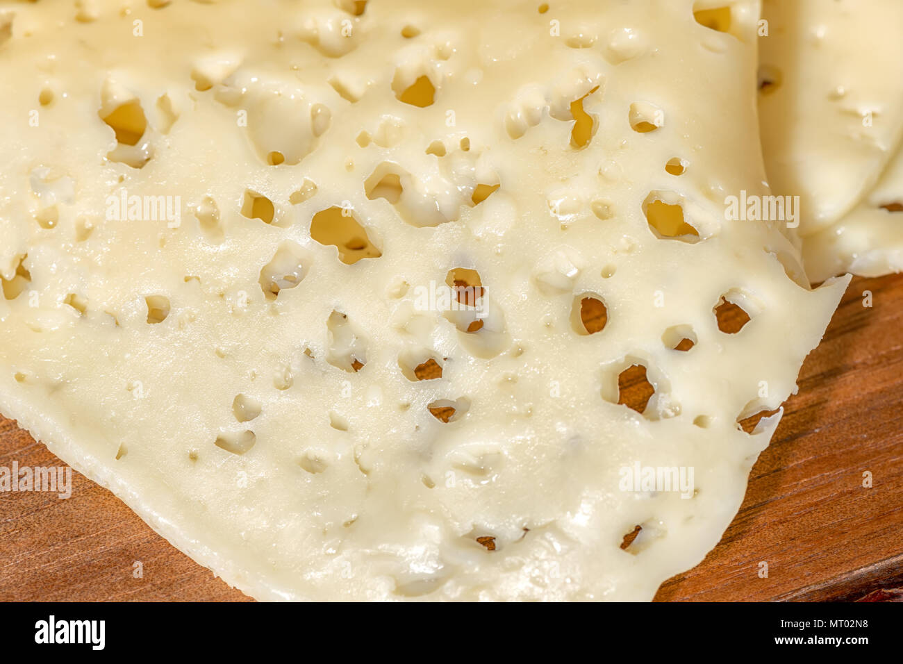Nahaufnahme der Bohrungen Käse in Scheiben geschnitten auf Holz Textur, Molkereiprodukte Stockfoto