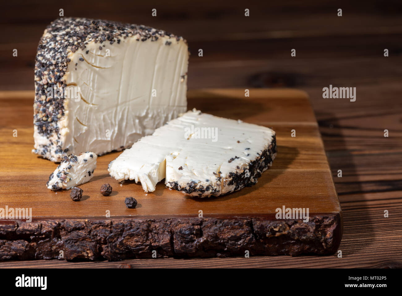 Weißer Käse mit geriebenem Pfeffer schwarz auf Holz Textur Stockfoto