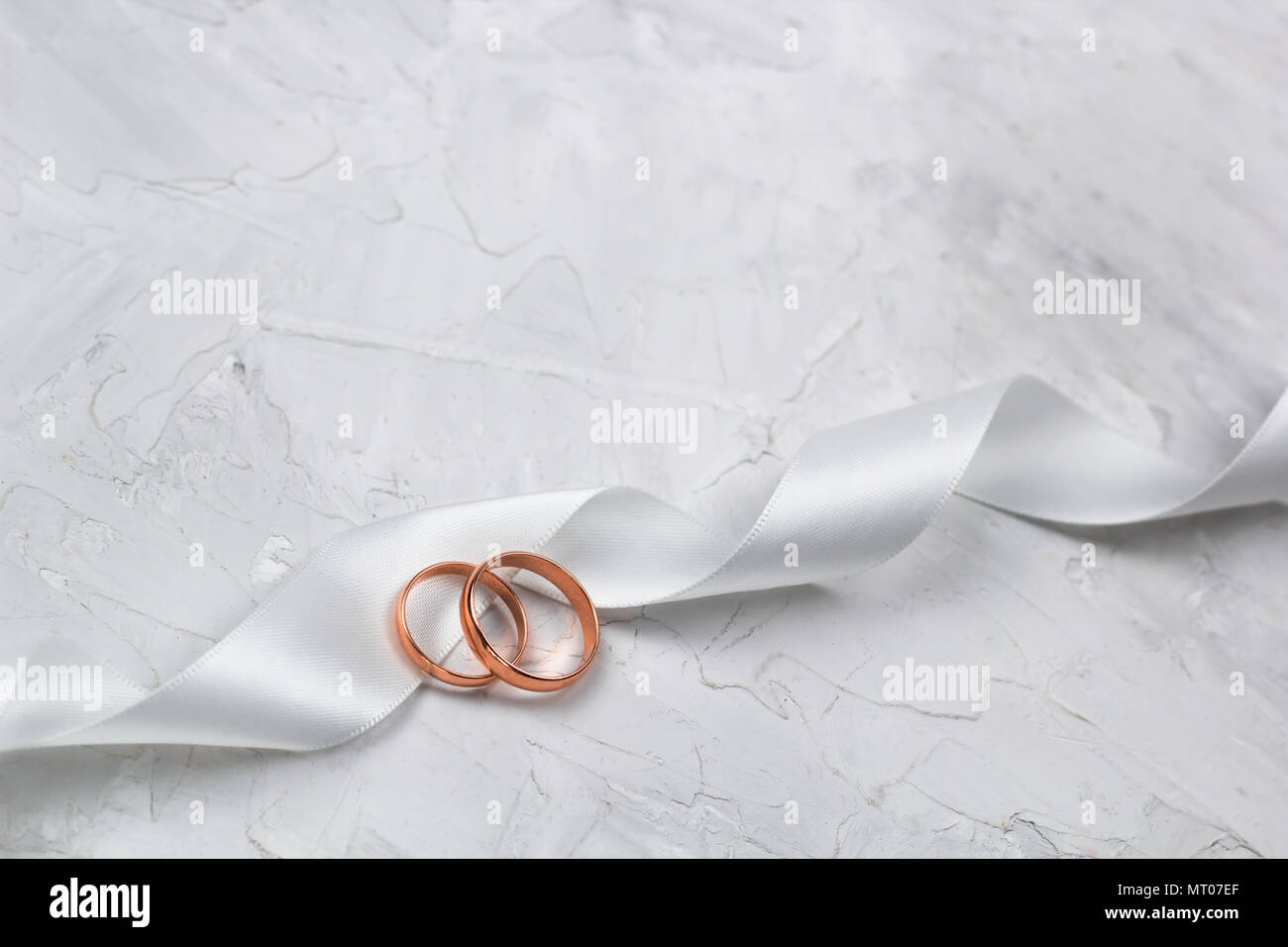Zwei goldene Ringe und Weiß Satin Band Hochzeit Dekor oder Hochzeit  Einladung Hintergrund Konzept Stockfotografie - Alamy