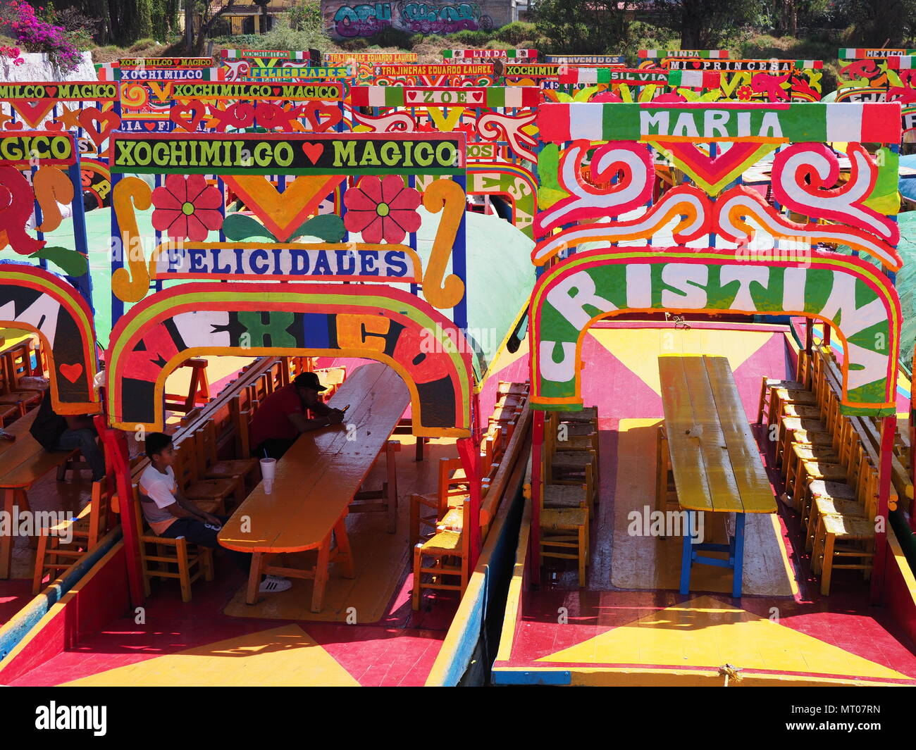 XOCHIMILCO, MEXIKO IM MÄRZ 2018: Farbenfrohe mexikanische Boote mit Frauen namen an schwimmenden Gärten in warmen, sonnigen Wintertag. Stockfoto
