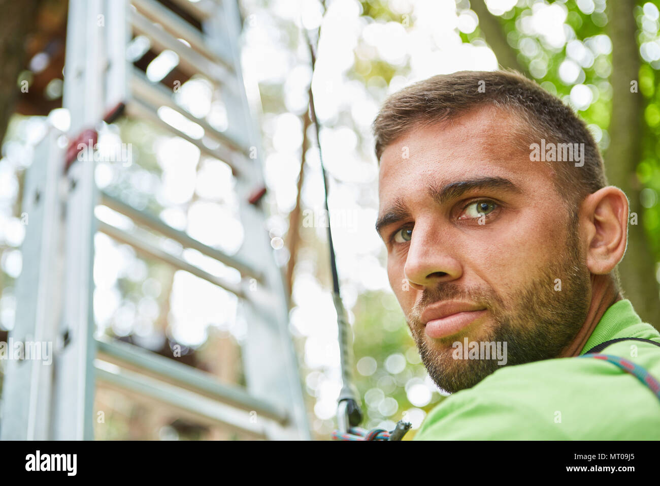 Angst junger Mann steht vor der Leiter in der Hochseilgarten in den Kletterpark Stockfoto