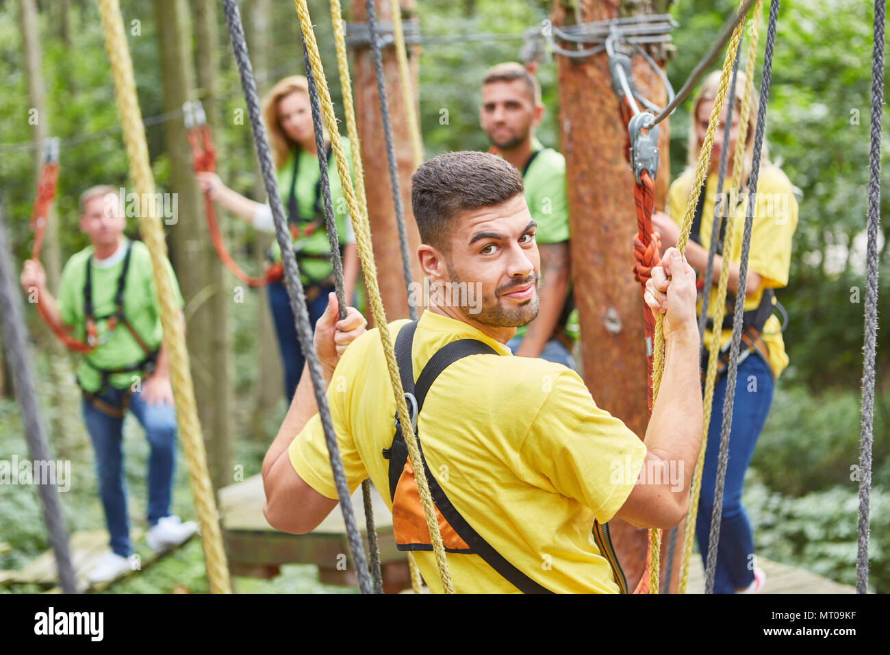 Junger Mann und sein Team zusammen im Hochseilgarten am Teambuilding Event Stockfoto