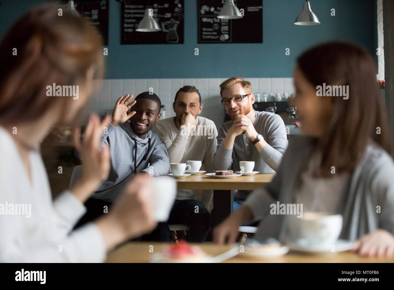 Afrikanische lächelnden Mann winkende Hand Gruß Mädchen treffen im Cafe Stockfoto