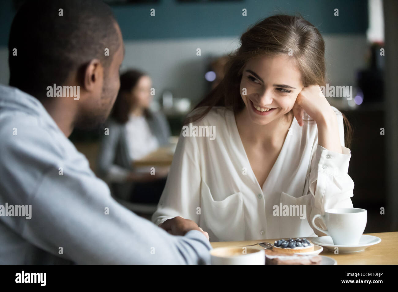 Glückliche junge interracial Paare flirten Reden halten sich an den Händen in Stockfoto