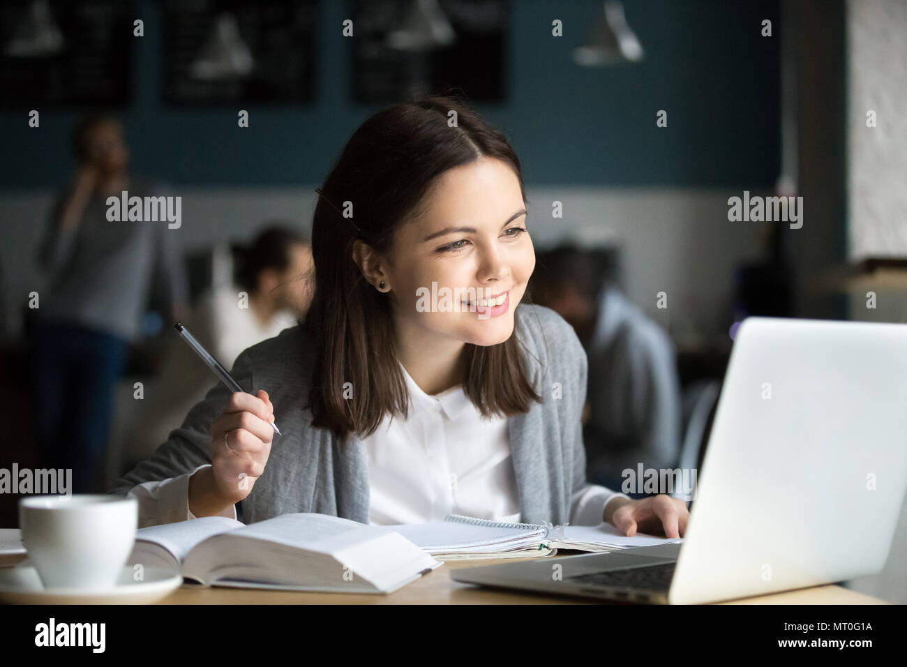 Lächelnde Mädchen am Laptop Notizen im Cafe sitzen auf der Suche Stockfoto
