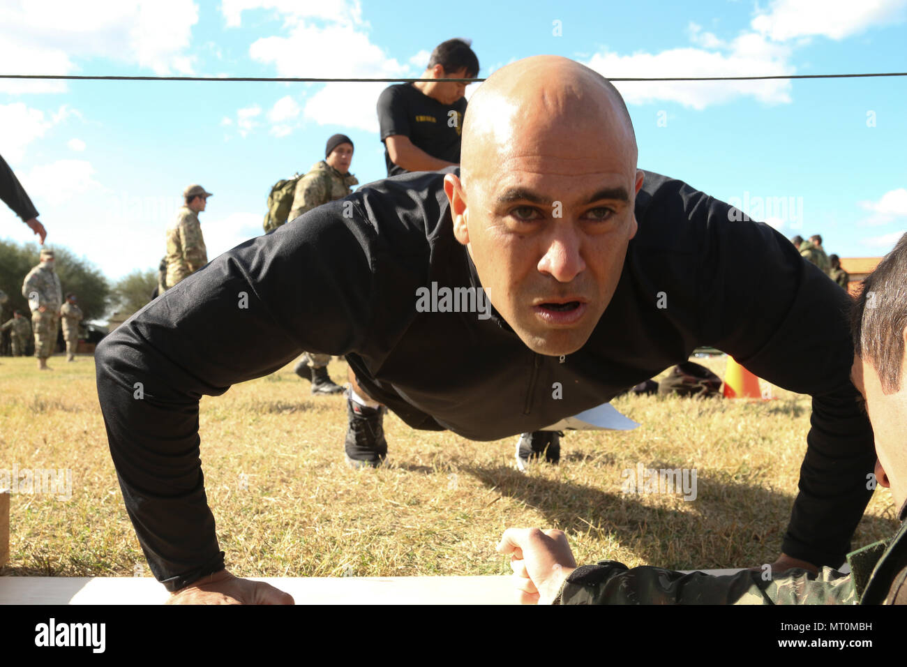 Ein Mitglied von Team Uruguay hilft, seine Mannschaft mit einem guten Ergebnis in der Push-up-Veranstaltung während der fuerzas Comando Wettbewerb Juli 17, 2017 bei Vista Alegre im Presidente Hayes, Paraguay. Die körperliche Fitness Test umfasst Liegestütze, Sit-up, Pull-up- und ein 4-Meile laufen, und ist die Kick-off-Veranstaltung zu den 2-wöchigen Übung. (U.S. Armee Foto von SPC. Elizabeth Williams/Freigegeben) Stockfoto