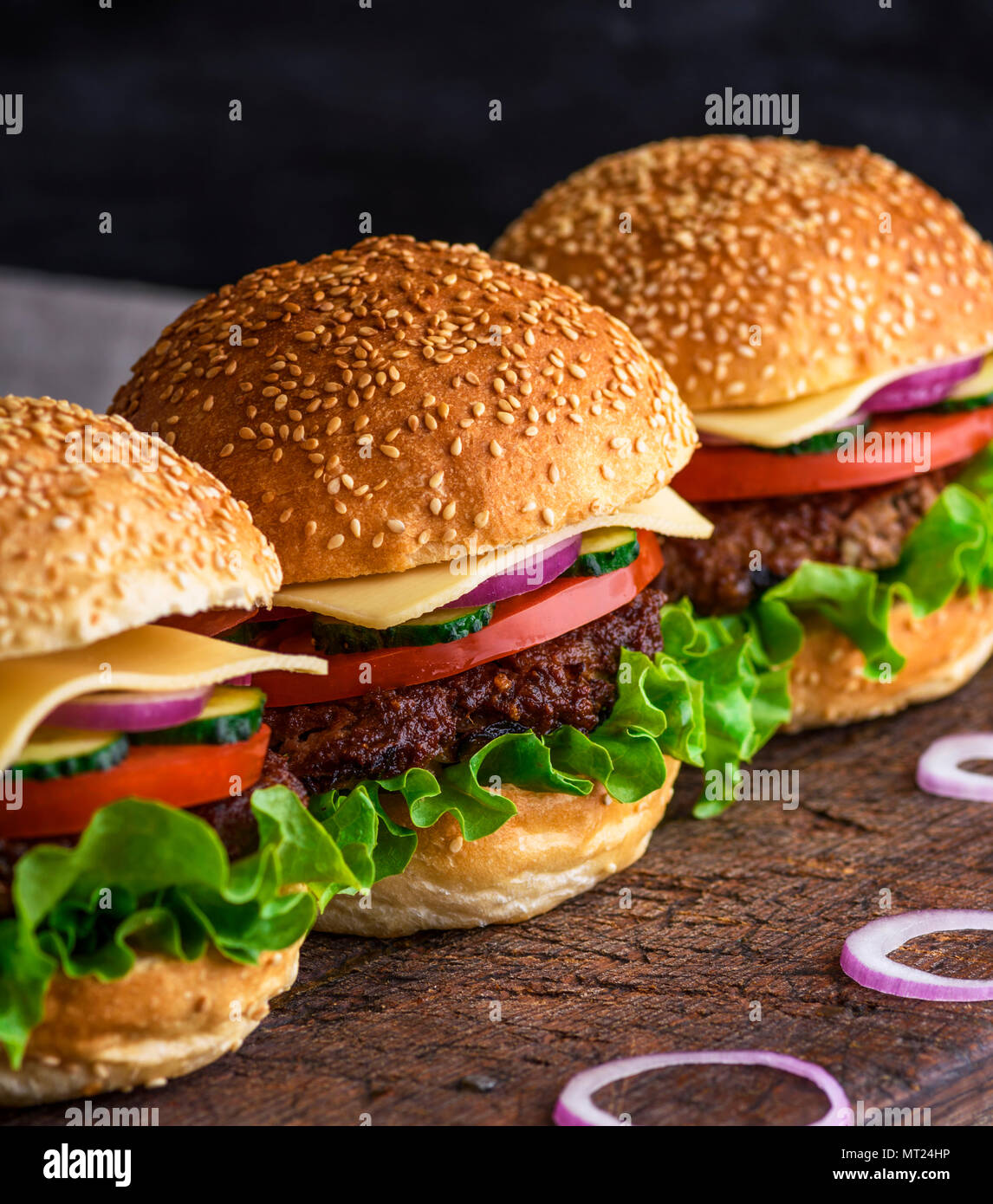 Hamburger mit Rindfleisch, Käse und Gemüse auf rustikalen braunen Tisch, Nahaufnahme Stockfoto