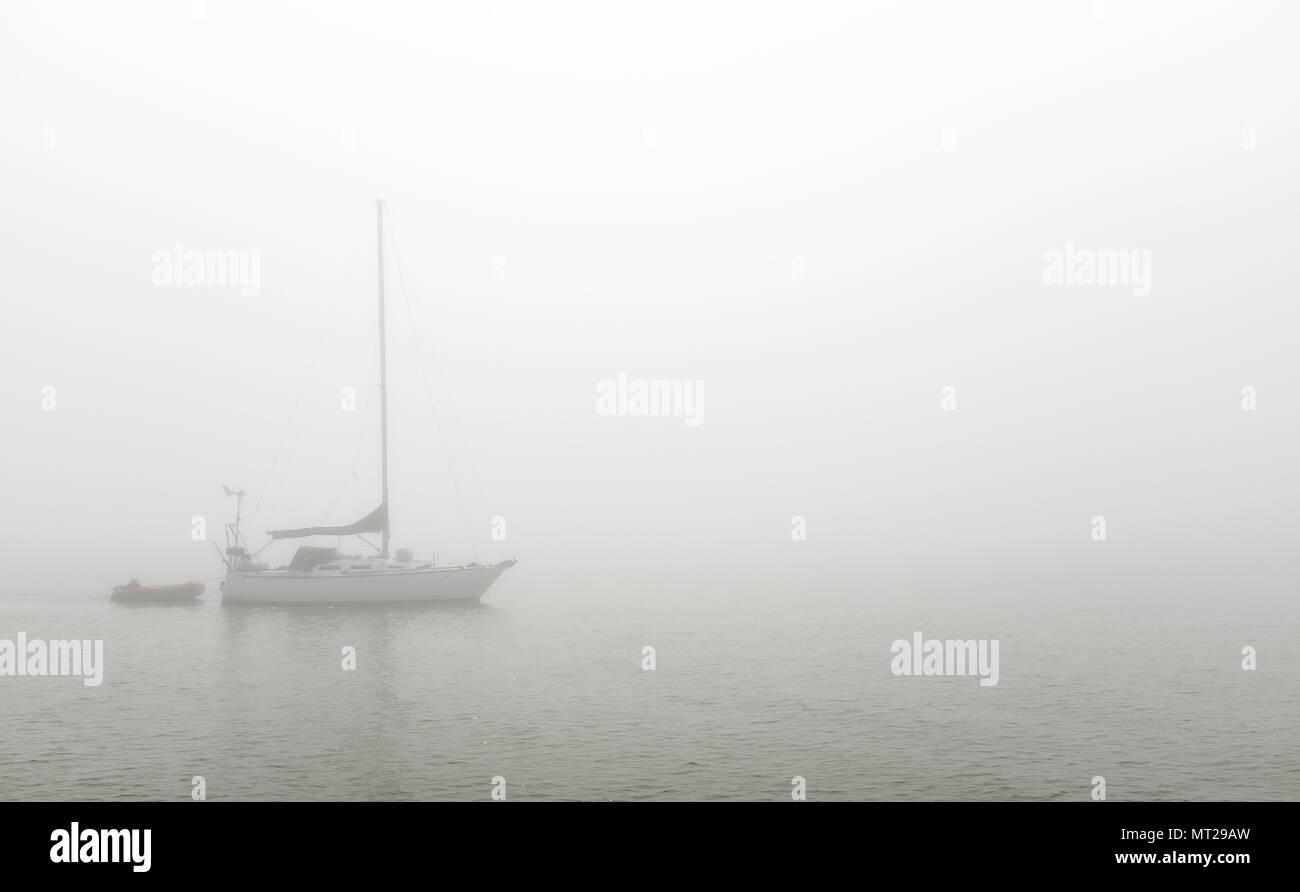 Kajakfahrer und Sportboote in Port Stanley Hafen unter einer Decke von dichtem Nebel. Stockfoto