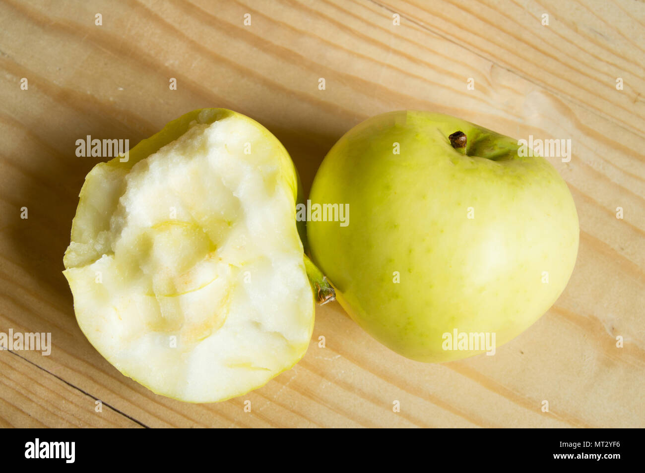 Reif Grün gebissen und ganzen Apfel auf einer hölzernen Hintergrund. Stockfoto