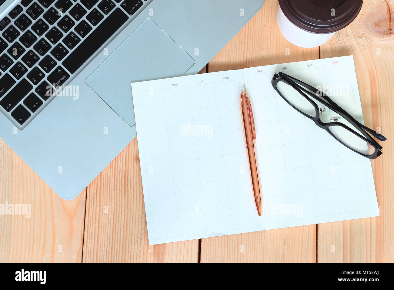 Stift und Brille lag auf leere Tagebuch Buch und Labtop und Kaffee Tasse auf Holz Tisch, Geschäftskonzept. Stockfoto