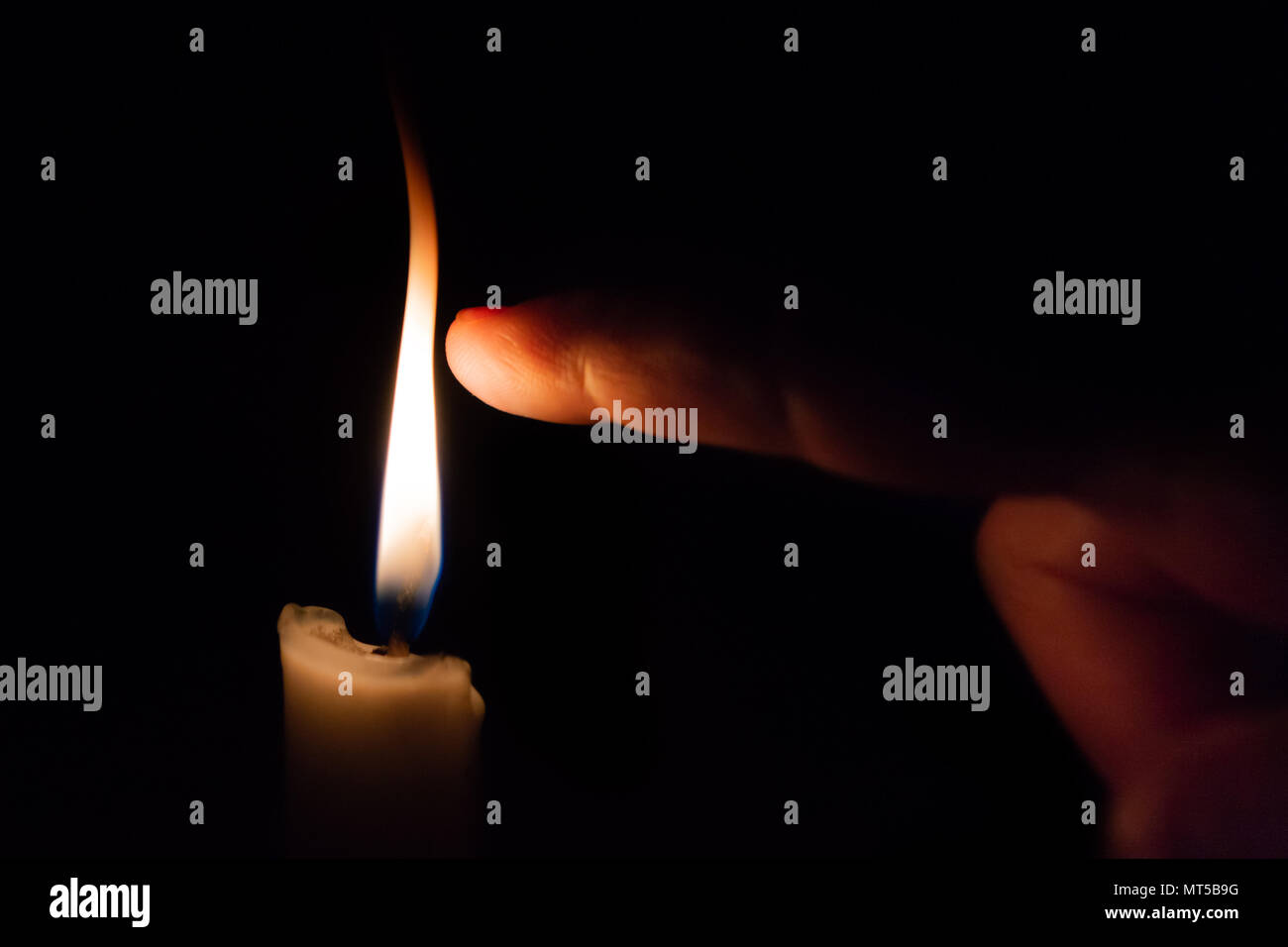 Eine Person nimmt seine Finger ganz in der Nähe der Kerze Flamme Stockfoto