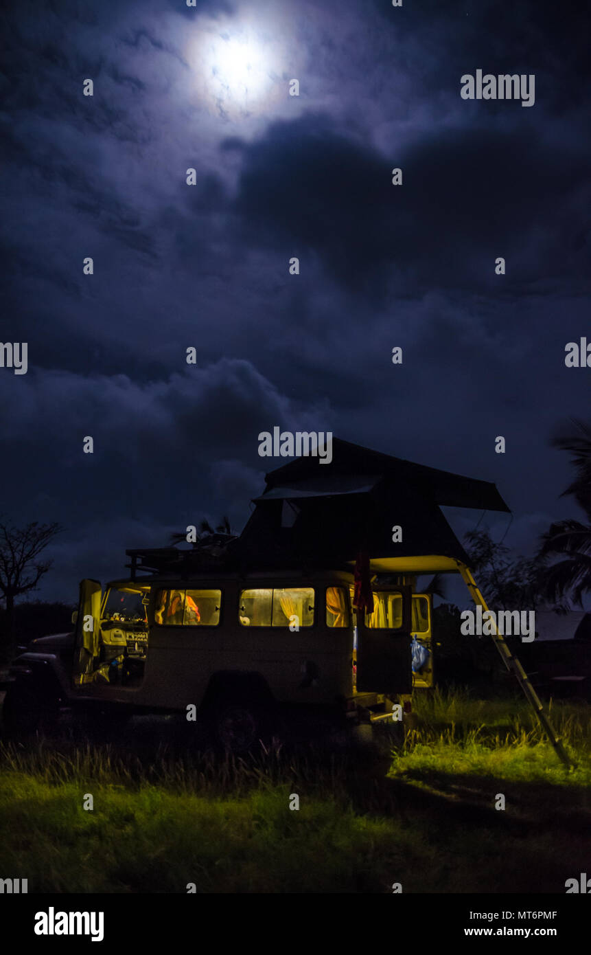 4x4 Geländewagen mit Dachzelt und das innere Licht während der Nacht mit bewölktem Himmel und starken Mond, camping Konzept Stockfoto