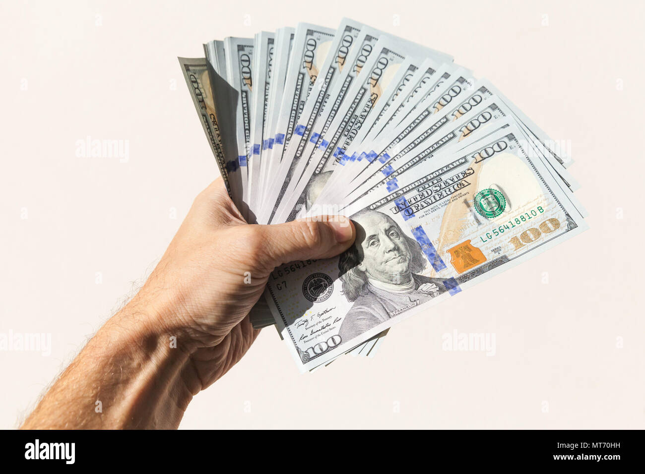 Fan von 100 Dollar Noten in männlicher Hand über grauer Hintergrund Stockfoto
