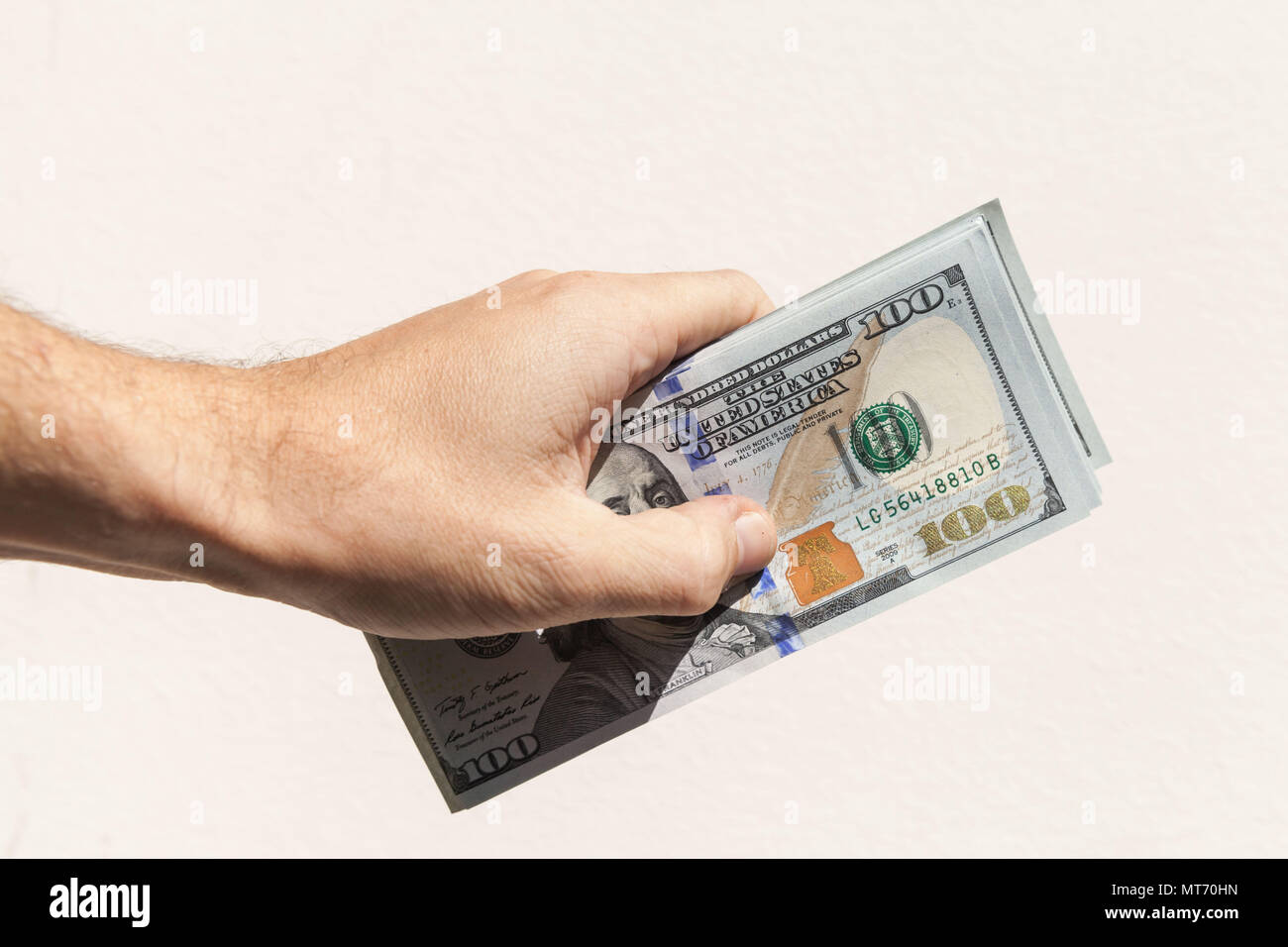 US-Dollar Noten in männlicher Hand über grauer Hintergrund Stockfoto