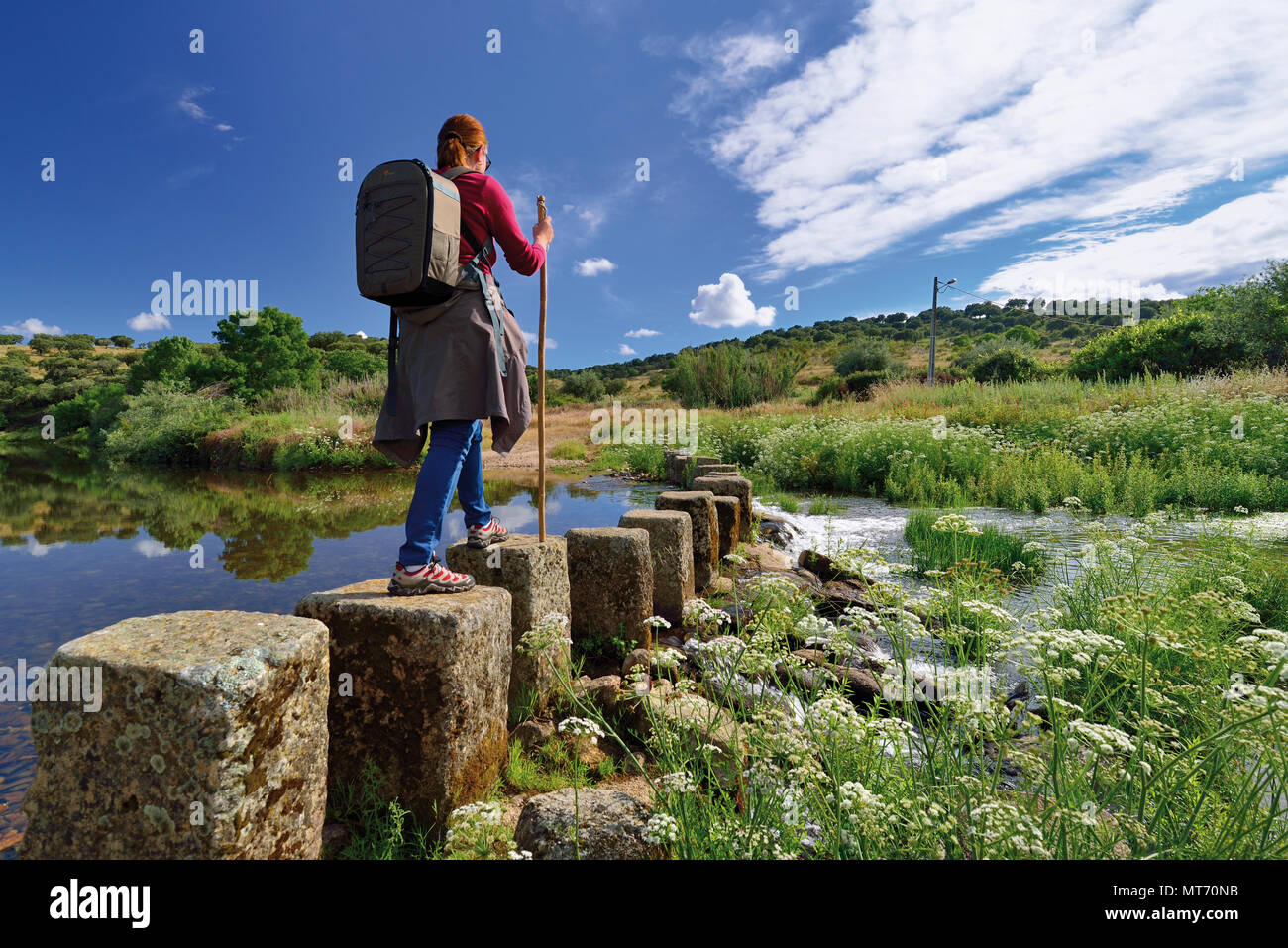 Frau mit Stock Kreuzung Trittsteine durch Fluss Ponsul Stockfoto