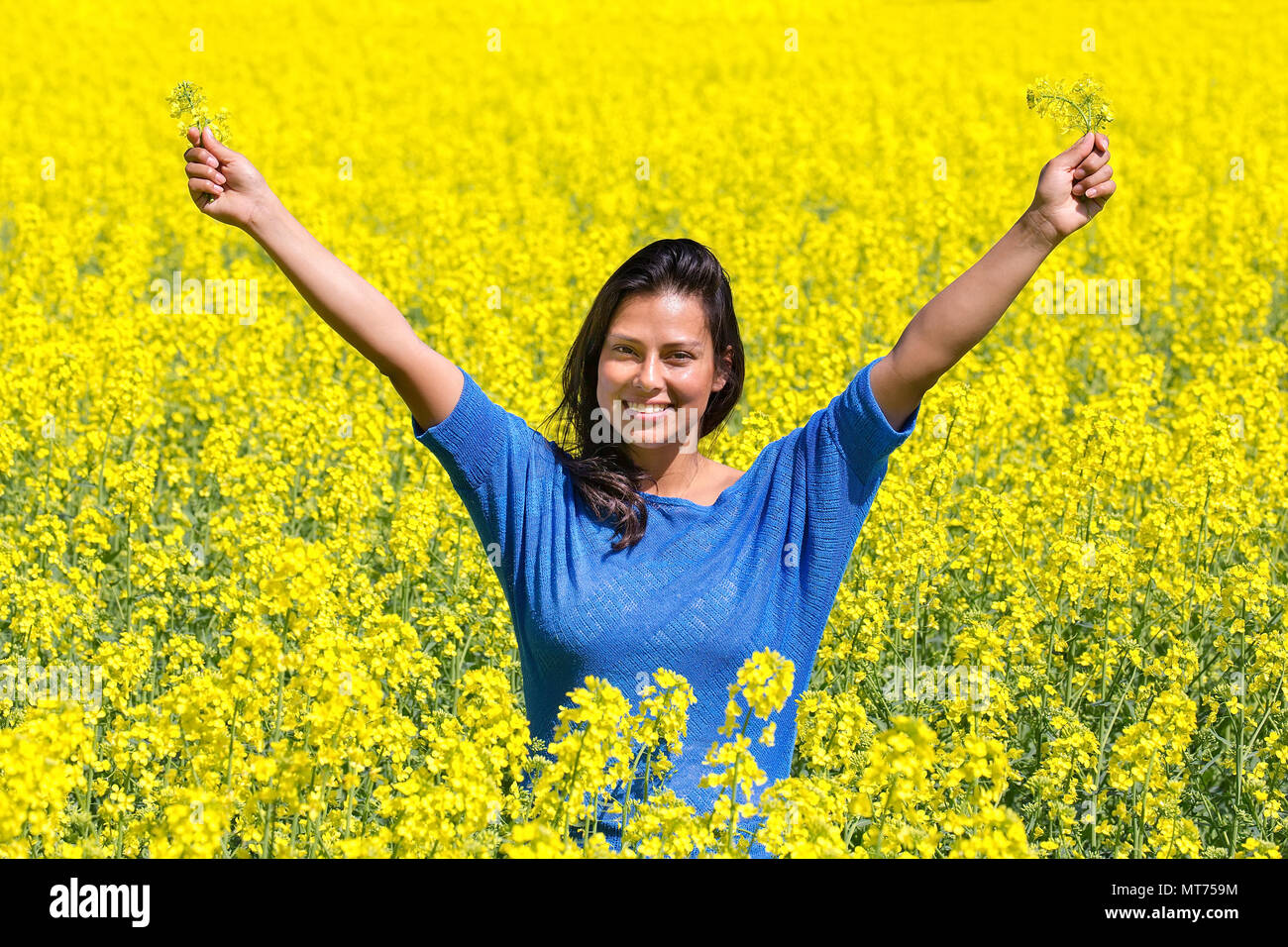Junge glücklich kolumbianische Frau Arme bis in gelber Raps Feld Stockfoto