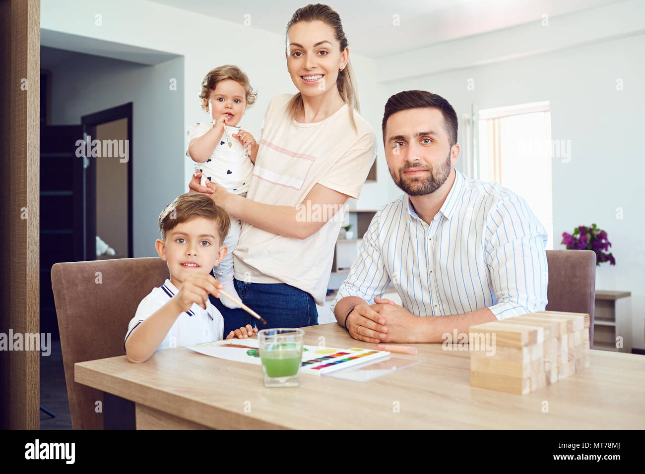 Glückliche Familie zieht malt auf ein Papier auf den Tisch. Stockfoto