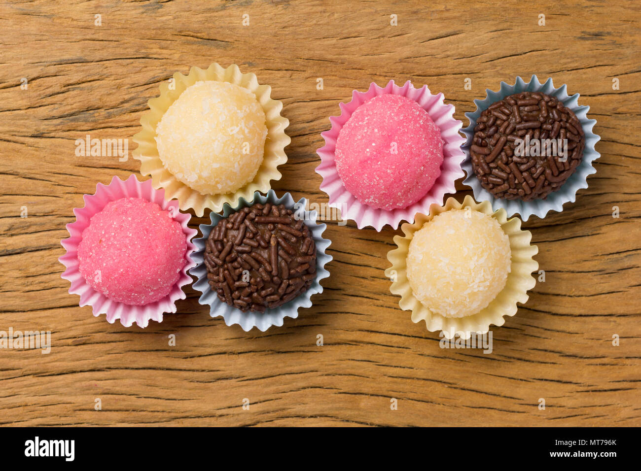 Brasilianische Spezialitäten: Brigadeiro, Beijinho und Bicho de Pe. Kindergeburtstag. Overhead von candy Ball auf rustikalen Holztisch. Stockfoto