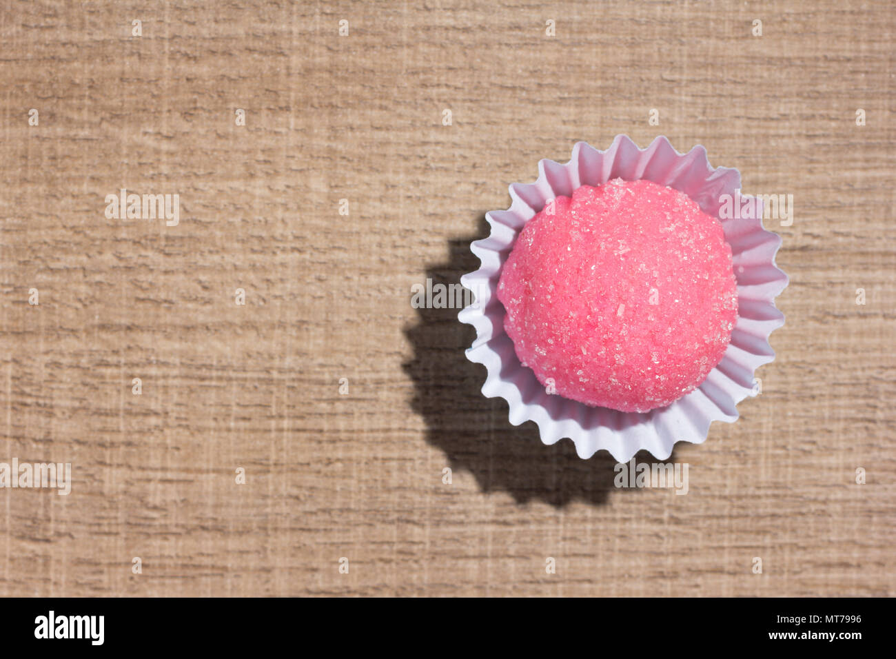 Bicho de pe ist eine Erdbeere flovoured brasilianischen Süßigkeiten. In Kindergeburtstage süß. Flach Design der Süßigkeit, die Kugel über Holz. Stockfoto