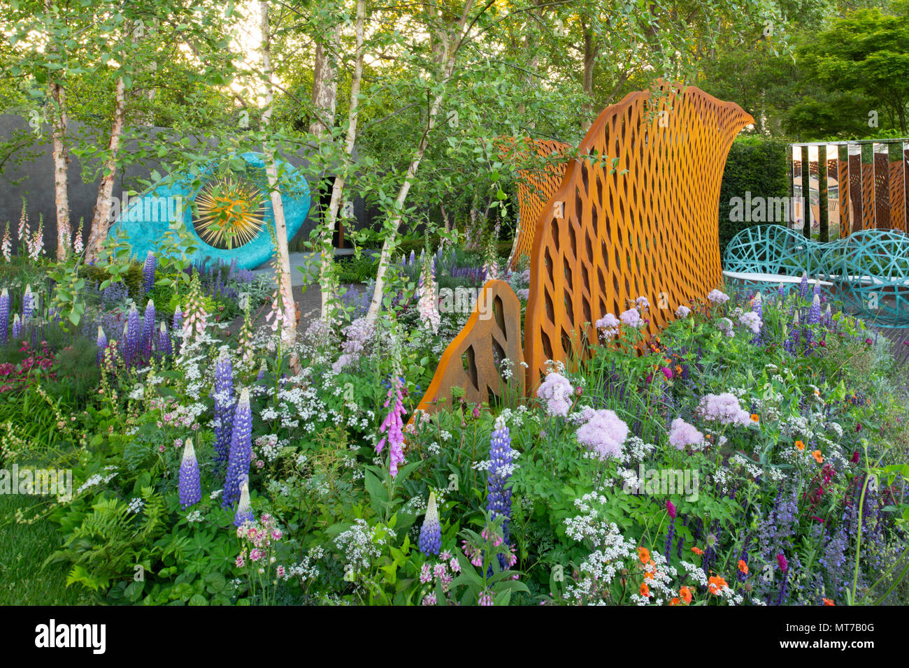 Auffällige Skulpturen und dichte Bepflanzung der Campanula glomerata 'West Country Persian Slipper" und einer Vielzahl von Pflanzen in der David Harber und Savills Gard Stockfoto