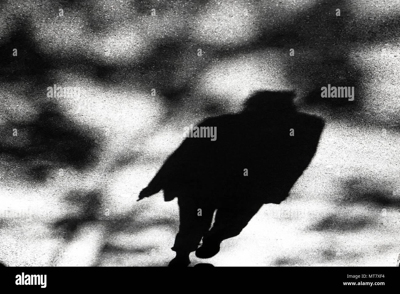 Schatten Silhouette eines Mannes gehen unter Baumkronen auf Stadt Straße in Schwarz und Weiß Stockfoto