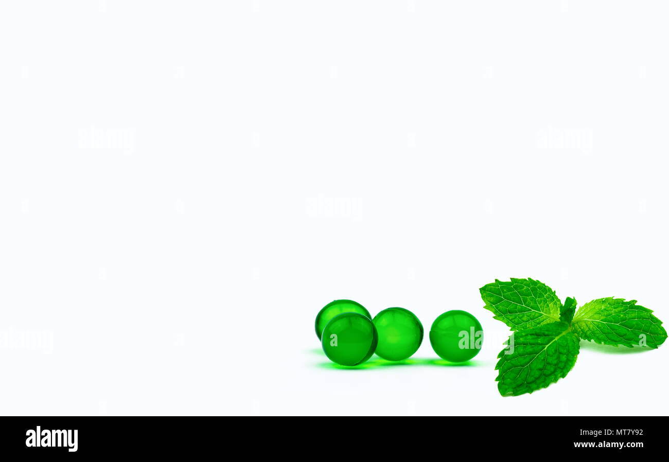 Grüne runde Weichkapsel Pillen und Minze auf weißem Hintergrund mit Kopie Raum isoliert. Die ayurvedische Medizin für Verdauungsbeschwerden, Gas- und Säuregehalt. Kraut Stockfoto